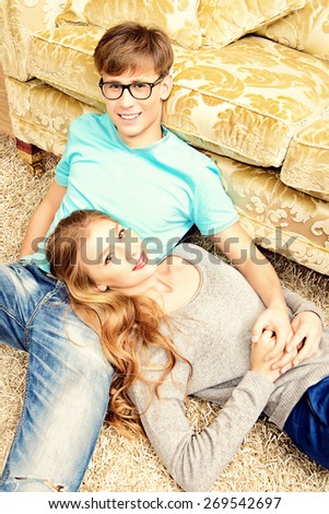 Beautiful young couple in love lying relaxed on a floor. They are in the cozy living room of their home. 