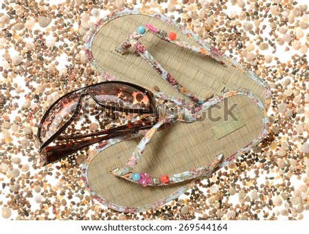 Braided barefoot persons sandals and women's sunglasses on a background of sea cockleshells and pebbles of stones Royalty-Free Stock Photo #269544164
