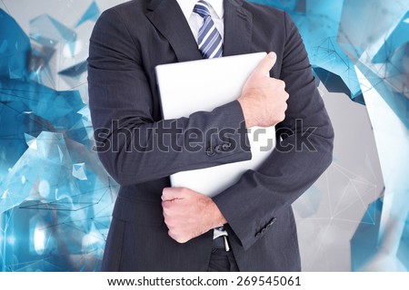 Businessman holding his laptop tightly against angular design