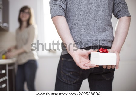 Man standing and holding white gift box behind his back