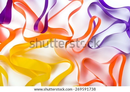 Background of orange, yellow, purple and blue twisted ribbons on a alight surface