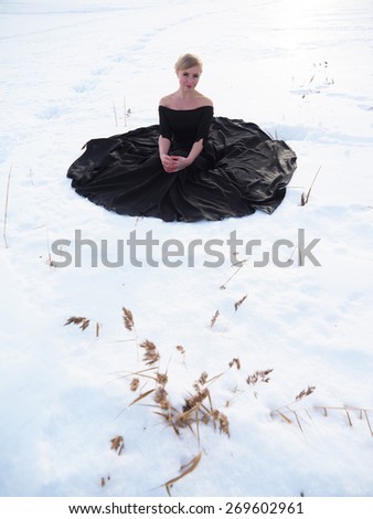 girl in black dress on the lake in winter