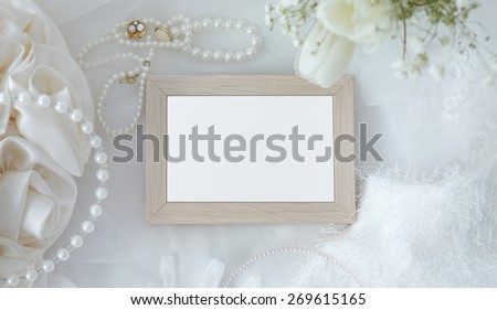 Blank wooden frame with flowers, jewelry, fur and accessories on white cloth background