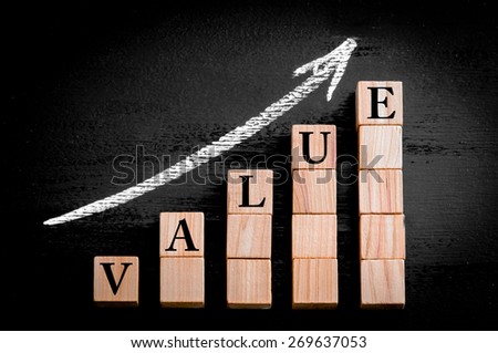 Word VALUE on ascending arrow above bar graph of Wooden small cubes isolated on black background. Chalk drawing on blackboard. Business Concept image. Royalty-Free Stock Photo #269637053