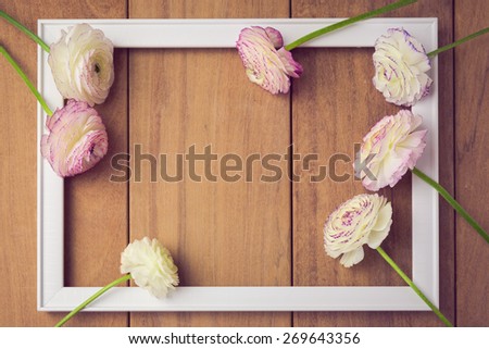 Background for wedding or party invitation. Picture frame with flowers on wooden table. View from above