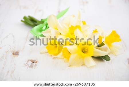 Bouquet of fresh spring narcissus flowers on white wooden background