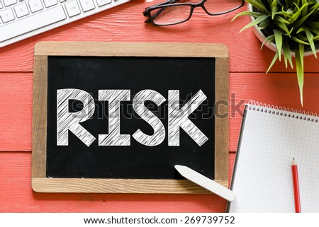 Risk word Handwritten on blackboard. Risk word Handwritten with chalk on blackboard, keyboard,notebook,glasses and green plant on wooden background
