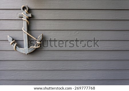 grey wooden anchor hundreds with white rope on wooden wall background