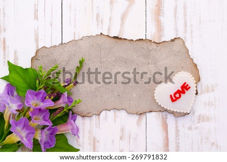 Background for greetings,Blank old brown paper with flowers and heart shape on wood table
