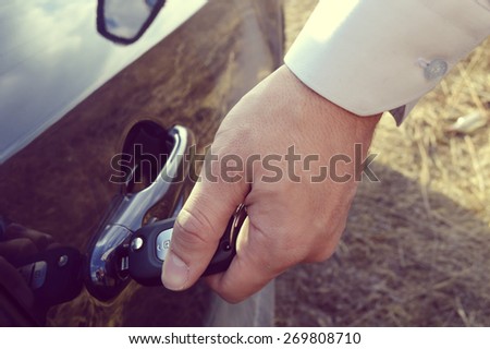 a hand holding a car's remote control pointing to the door.a man opens a machine
