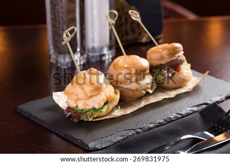 Three hamburgers with shrimp, chicken and beef on stone board on the table