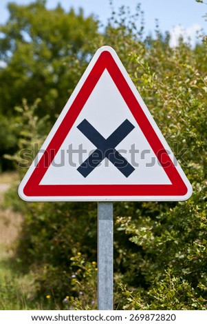 Triangular crossroads road sign on a country road junction