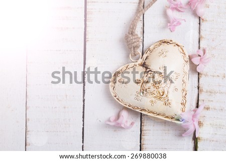 Decorative  heart  and little pink flowers in ray of light  on white  painted wooden background. Place for text. 