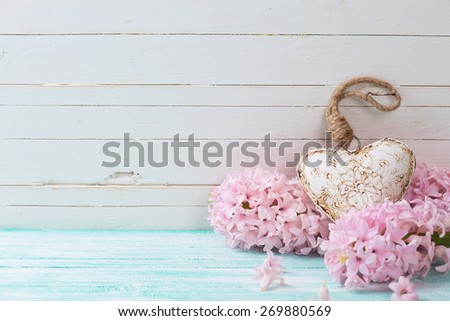 Background with fresh flowers hyacinths  and decorative heart in ray of light on turquoise painted wooden planks. Selective focus. Place for text.