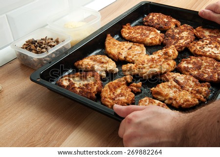 grilled chicken breast. meat is laid on a black pan, poured with sauce and melted cheese. Cooking meat at home in the oven.