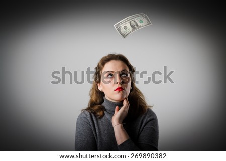 Girl in grey and falling dollar banknote. Currency and lottery concept.