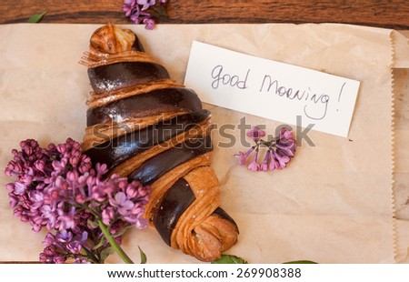 Croissant with good morning note and lilac on the paper background