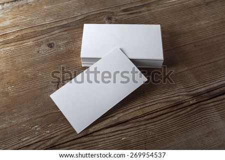 Blank white business cards on a dark wooden background. Mockup for branding identity. Template for graphic designers portfolios. Top view. Shallow depth of field. 