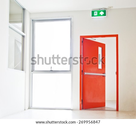 Building Emergency Exit with Exit Sign, red door opening to white