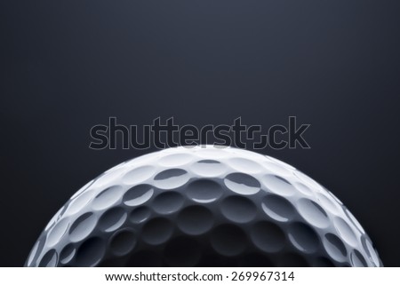 Stylish golf ball isolated on empty dark blue background, close up shot with  blank space for text.