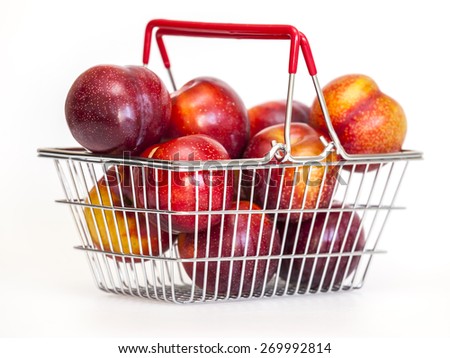 Large red plums in a metal basket for purchases