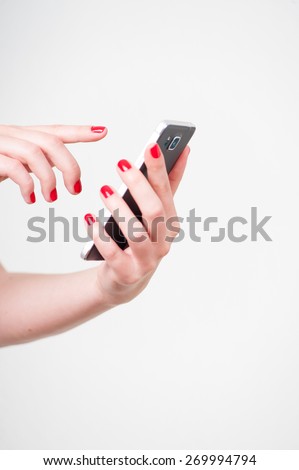 Close up image of red nailed womans hands holding touch screen mobile smartphone on isolated white background