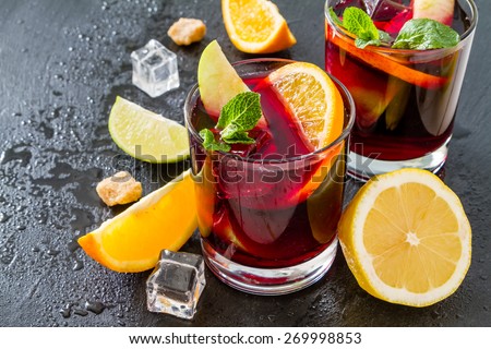 Sangria in glasses with ingredients - orange, lemon and lime slices, sugar, dark stone background Royalty-Free Stock Photo #269998853