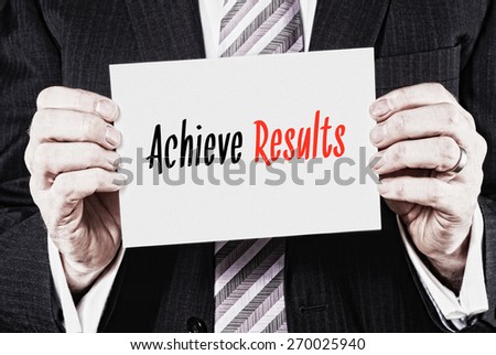 A businessman holding a card with the words,  Achieve Results.