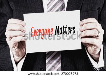 A businessman holding a card with the words, Everyone Matters written on it.