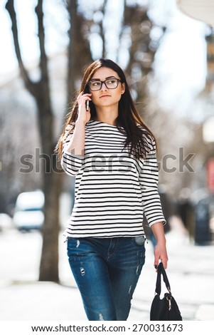 Beautiful model in a striped sweater and is talking on the phone.