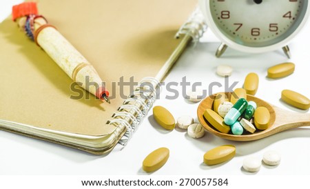 clock , notebook , pen and medicine vitamin capsules on white background.