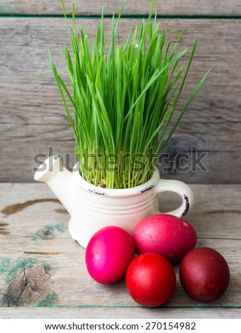 Easter eggs and grass in pot  on wooden background