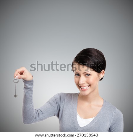 Girl hands a silver key, isolated on grey