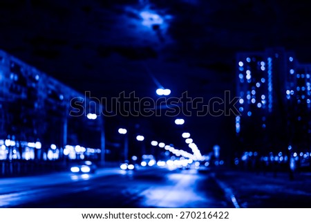 Night city after rain, the moon over the road on which the car ride. Defocused image, in the blue toning