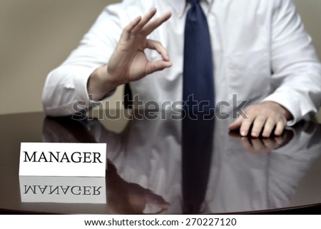 Manager sitting at desk holding OK sign to show deal is done