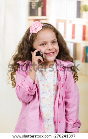 portrait of cute little happy girl using cell phone talking