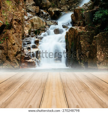 Brown wood floor perspective and natural mountain waterfall.