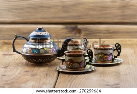 Traditional Turkish tea set: vintage painted copper cups with teapot on wooden table