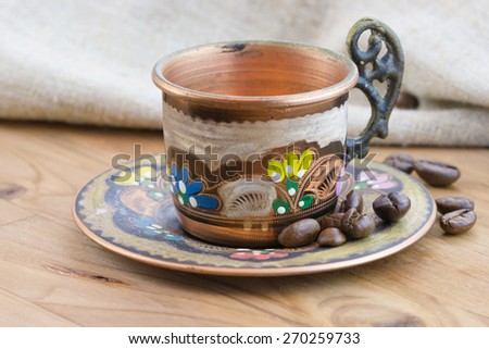 Old vintage traditional copper cup with roasted coffee beans and sackcloth on wooden table