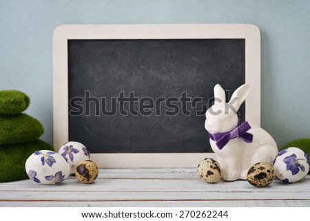 Framed blackboard with statuette of rabbit, easter eggs and decorative moss