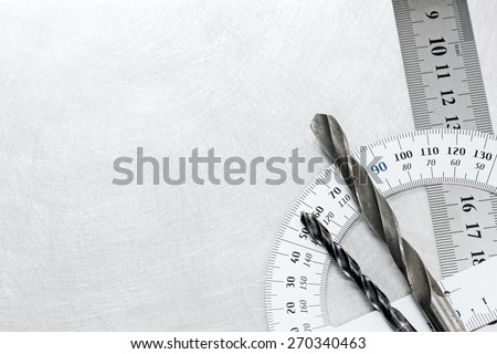 Drill bits with protractor and rule on scratched metal background