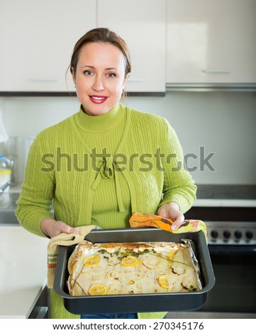 Smiling  housewife preparing slices of white fish for baking