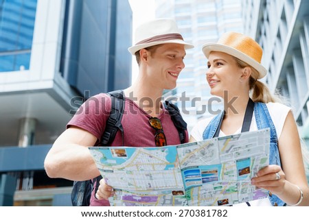 Happy young couple as tourists with a map