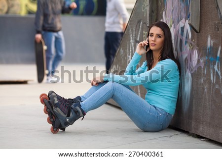 Teenage girl taking a break from roller skating to make a phone call