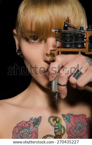 tattooed beautiful woman with tattoo machine, dark background