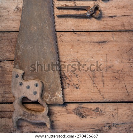 Color photo of vintage hand saw and wrench on the wooden grunge table with copy space