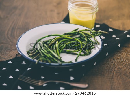 Boiled green asparagus dressed in mustard vinegar and olive oil dressing mayonnaise or hollandaise sauce. Toned picture