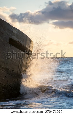 waves crushing over rocks and ruins of old fort at sunset on the beach
