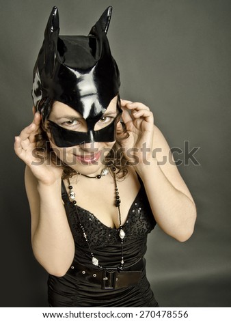 cheerful emotional beautiful girl on a dark background in dark clothes in a black mask cats