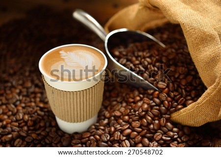 Paper cup of coffee latte and coffee beans on wooden table Royalty-Free Stock Photo #270548702